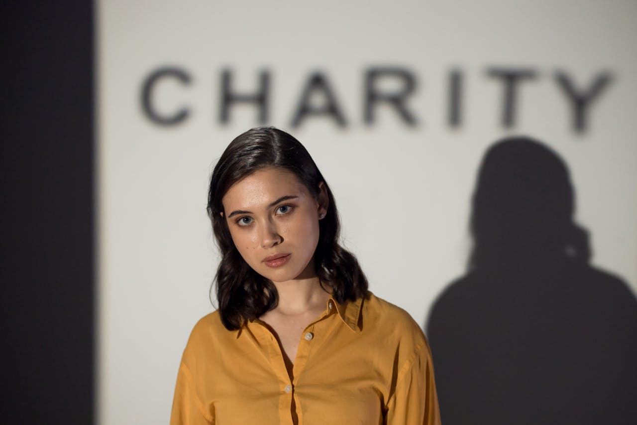 hero-img-02 A thoughtful woman stands before a charity-themed backdrop, evoking compassion and volunteerism.